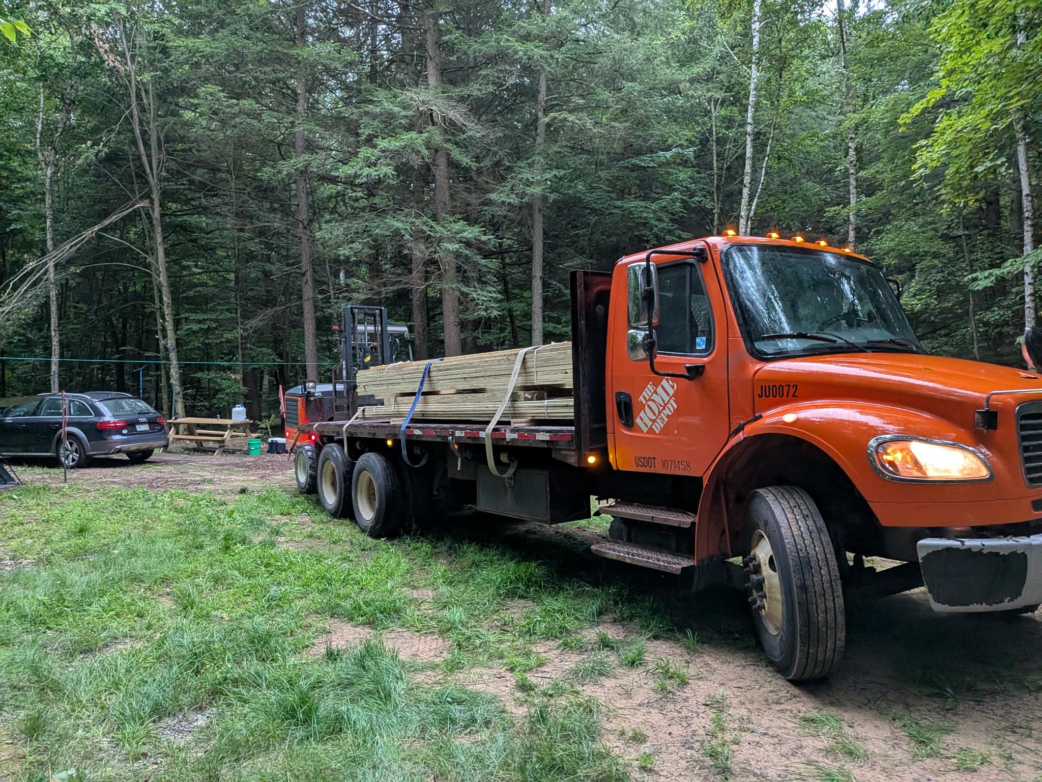 Flatbed truck delivering lumber to the wooded site