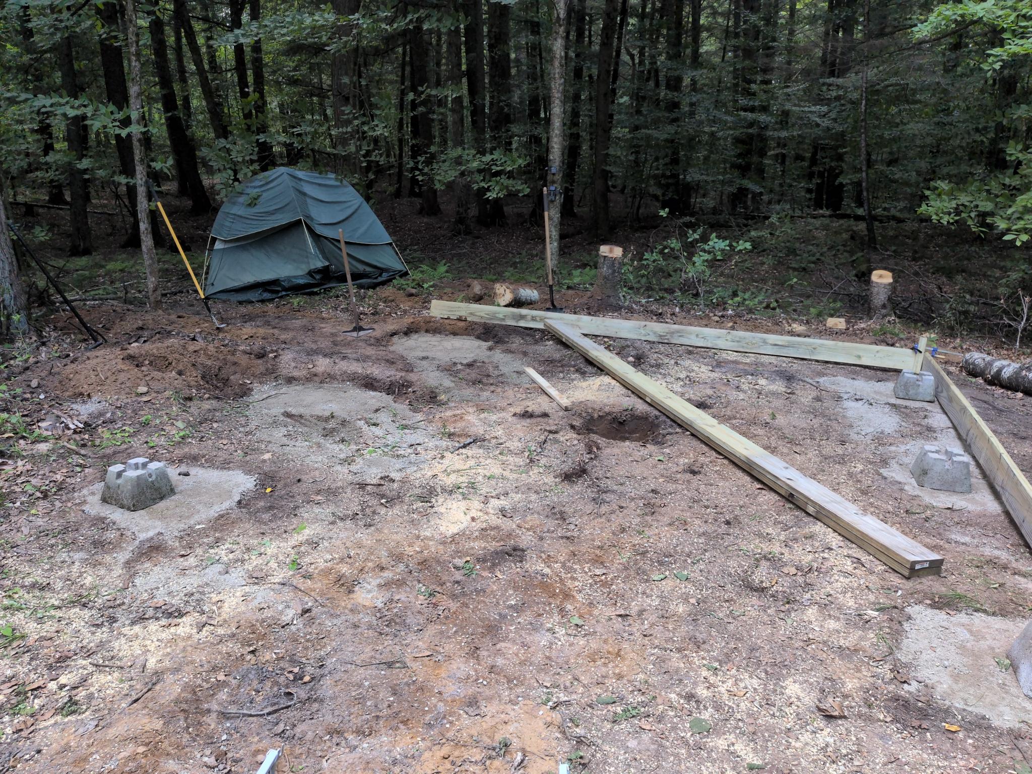 Cleared site with piers set and a tent in the background