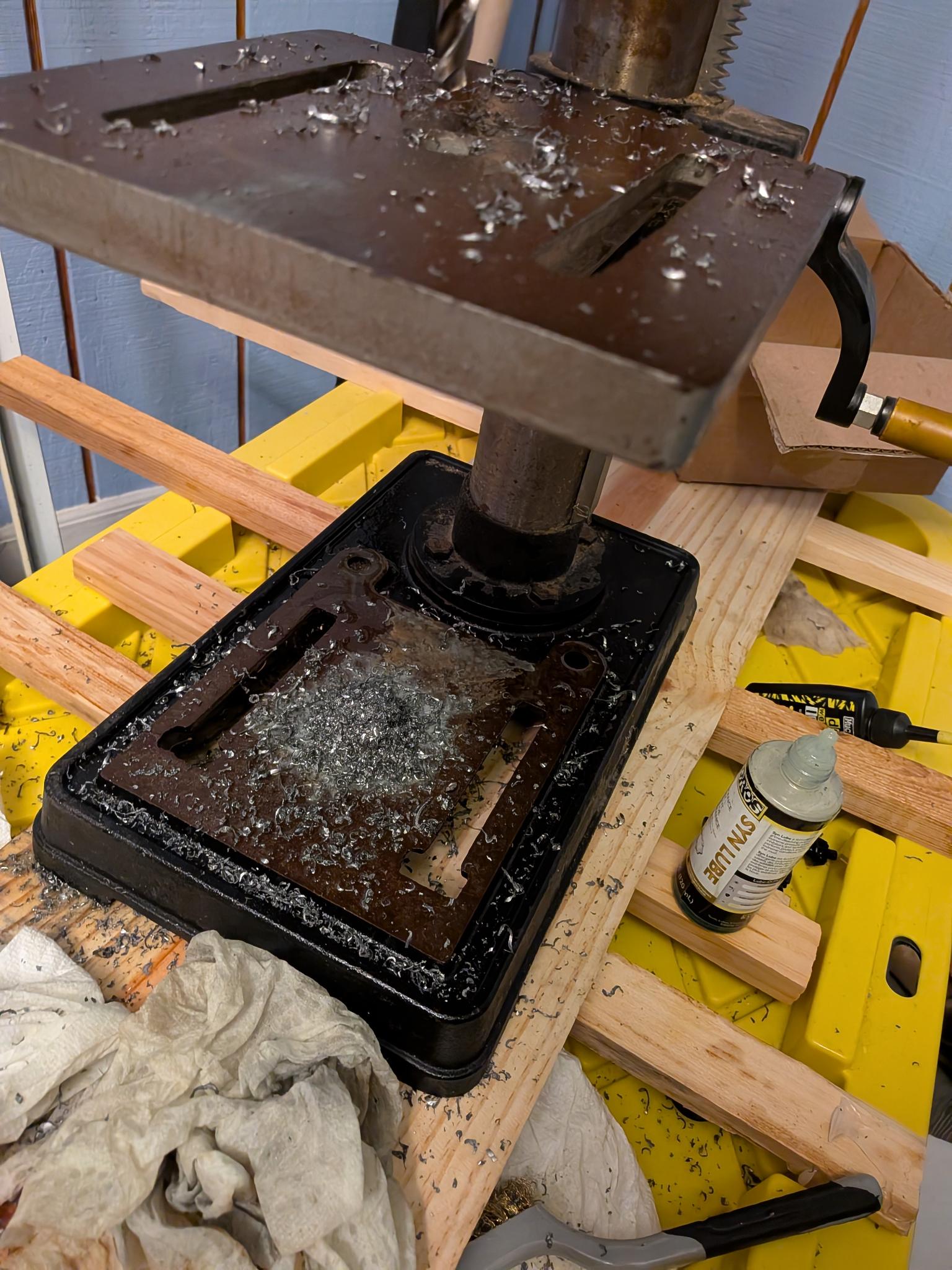 Drilling flattened conduit ends on a drill press with metal shavings
